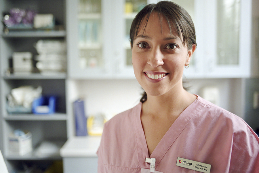 picture of clinician in scrubs in a clinical setting, with a Shield HealthCare nametag. registered dietitian vs nutritionist.