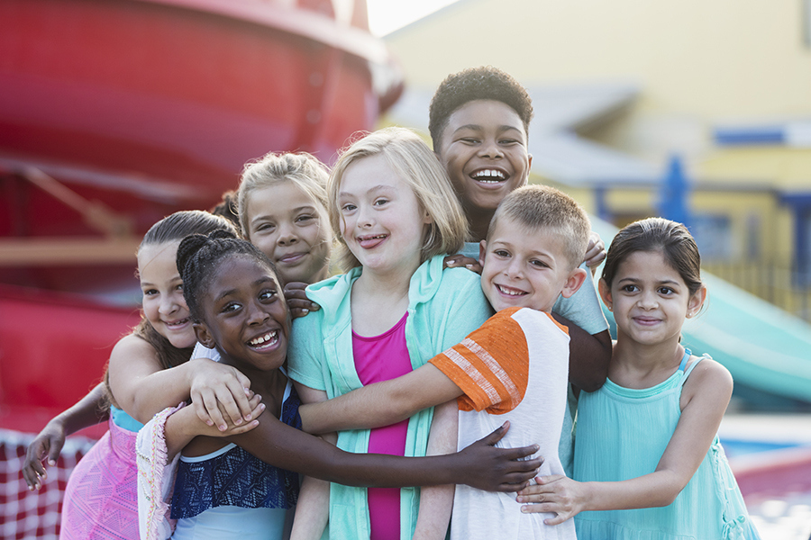 Girl with down syndrome, friends at water park hugging. Down Syndrome Awareness Month