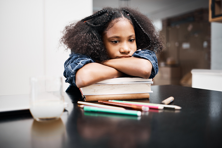 techniques to help children with ADHD study in school and at home. Image of middle-school-age girl with head on her books, staring listlessly into the distance.